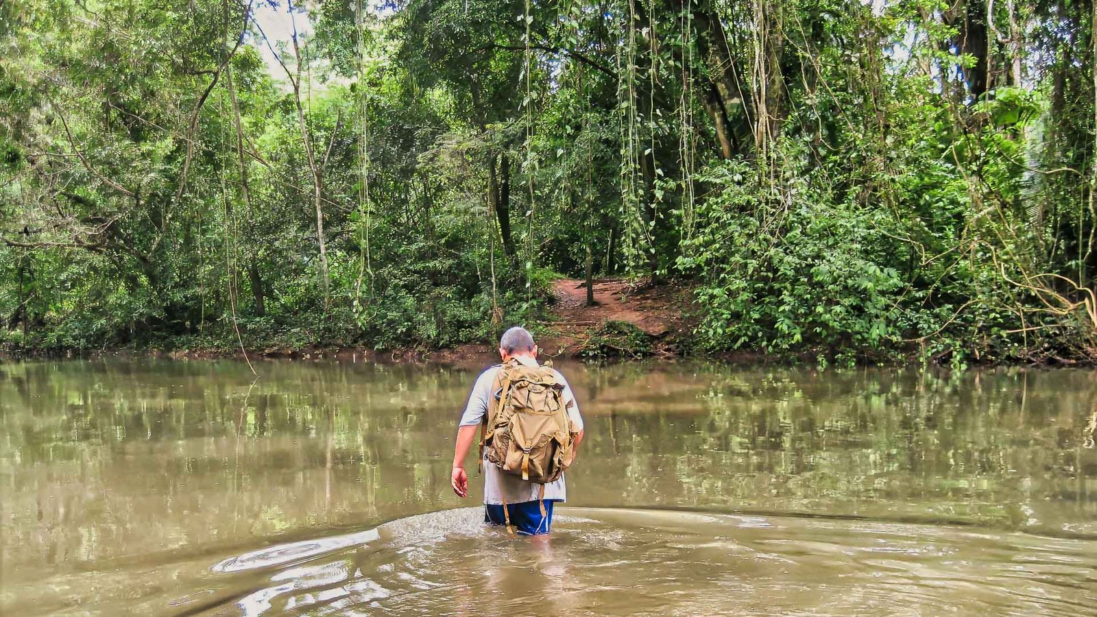 traveler walking across a jungle river on the Actun Tunichil Muknal tour in Belize