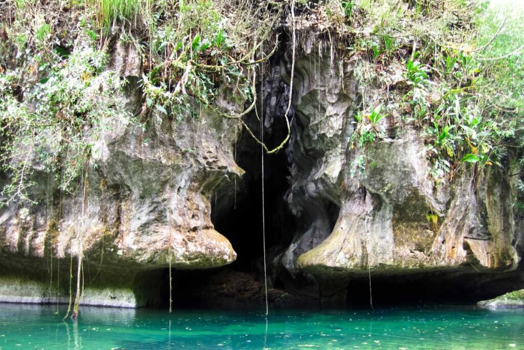 Jungle-framed entrance of Barton Creek Cave, a signature scene of the Barton Creek Canoe Tour.