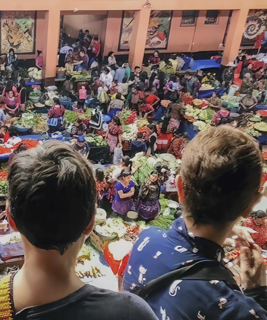 Couple admiring vibrant fruits and vegetables at Chichicastenango Market in Guatemala, a cultural highlight of the Ultimate Belize and Guatemala Itinerary.