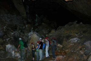 A group of explorers on the Crystal Cave Day Tour Belize marvel at a massive underground chamber adorned with shimmering crystal formations and ancient Maya artifacts.