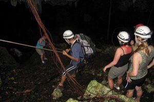 Group of adventurers trekking through the jungle on the Crystal Cave Day Tour Belize, heading toward the cave entrance in Blue Hole National Park.