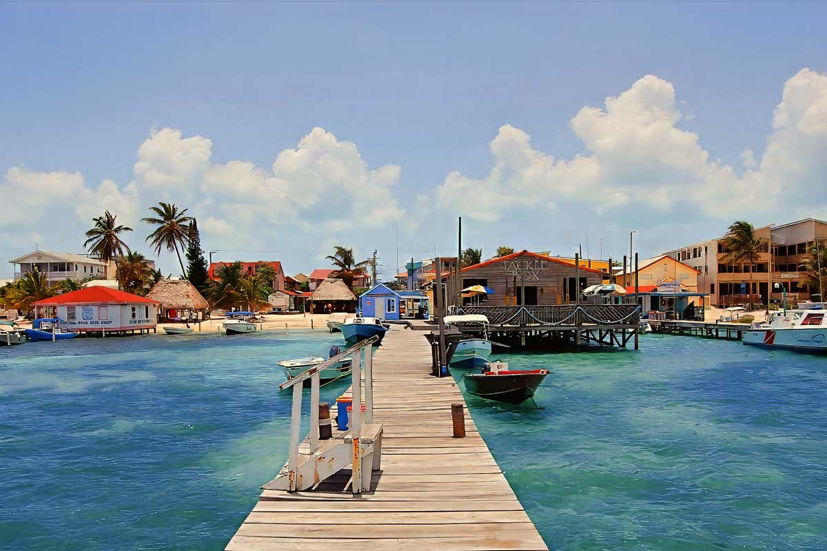 Wooden deck overlooking turquoise Caribbean waters with coconut trees and blue sky in Caye Caulker, showcasing why Belize is safe for tourists seeking tropical escapes.