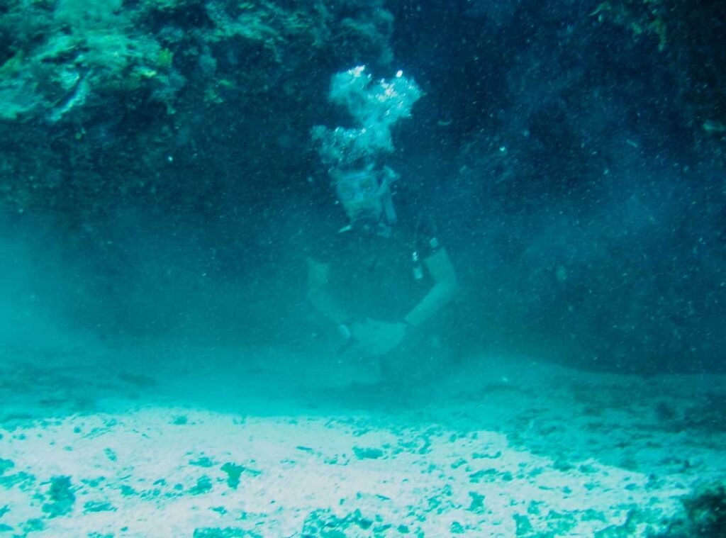 Scuba diver exploring vibrant coral reefs near a tropical Belizean caye in clear Caribbean waters