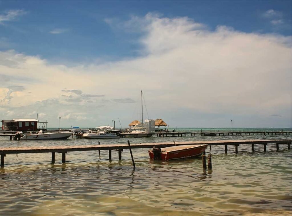Serene deck with boats docked in San Pedro on Ambergris Caye, Belize, overlooking calm Caribbean waters under a sunny sky.