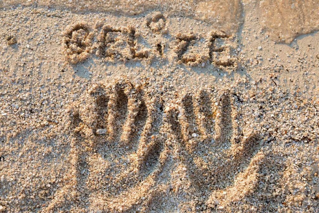 Belize - Authentic Travel Belize Handprints of a man and woman in the white sand on a tropical beach in Belize, symbolizing romance and connection — perfect for Belize vacation packages for couples.