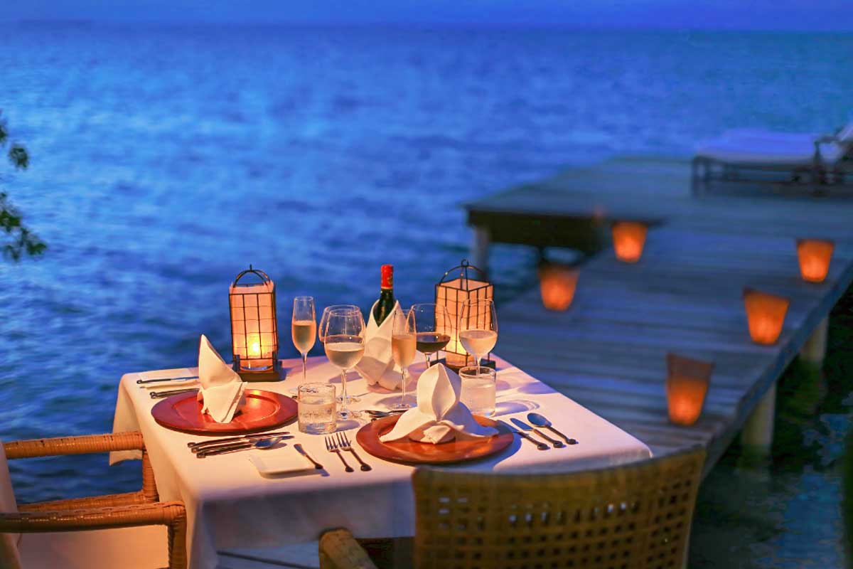 Romantic beachside candlelit dinner at sunset, part of Belize vacation packages for couples seeking luxury, privacy, and unforgettable tropical moments.