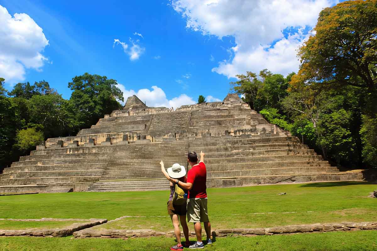 Couple standing in front of El Castillo at the Xunantunich Maya ruins during a package holidays to Belize cultural experience