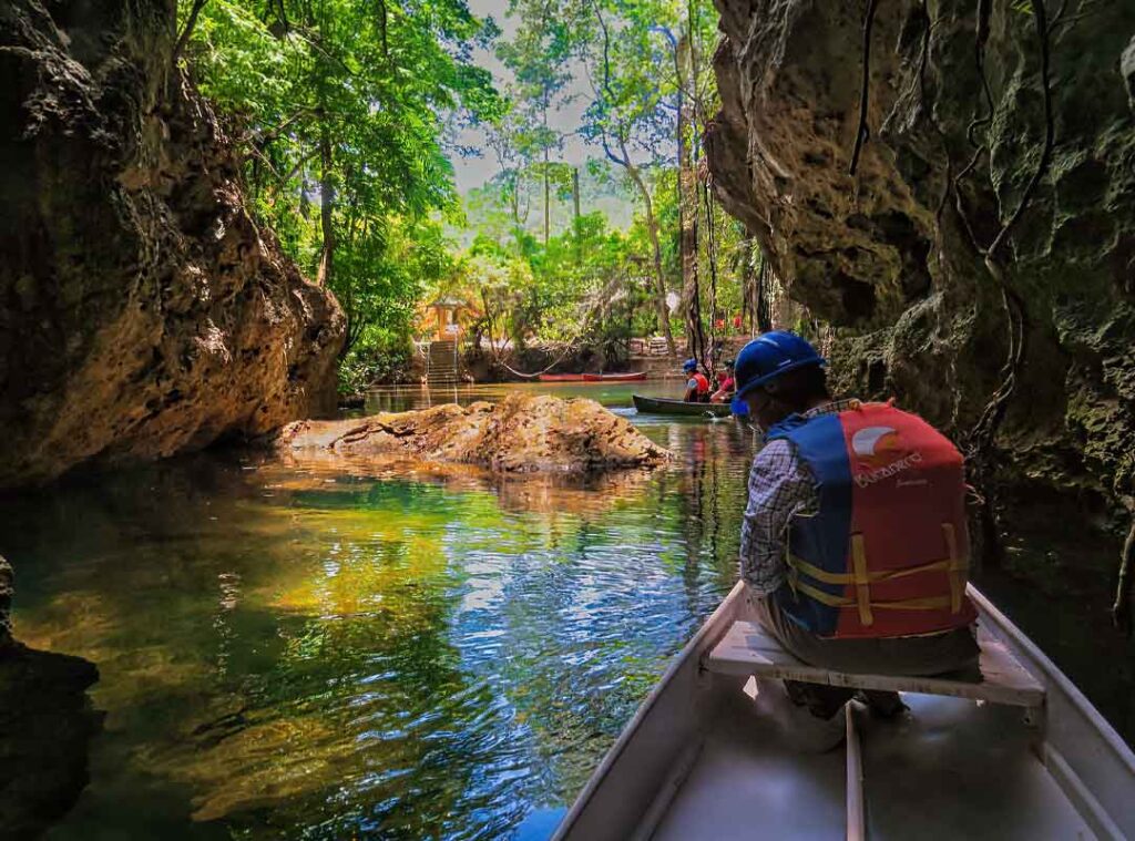 Visitor exiting Barton Creek Cave by boat during a cave tour in Cayo District Belize.