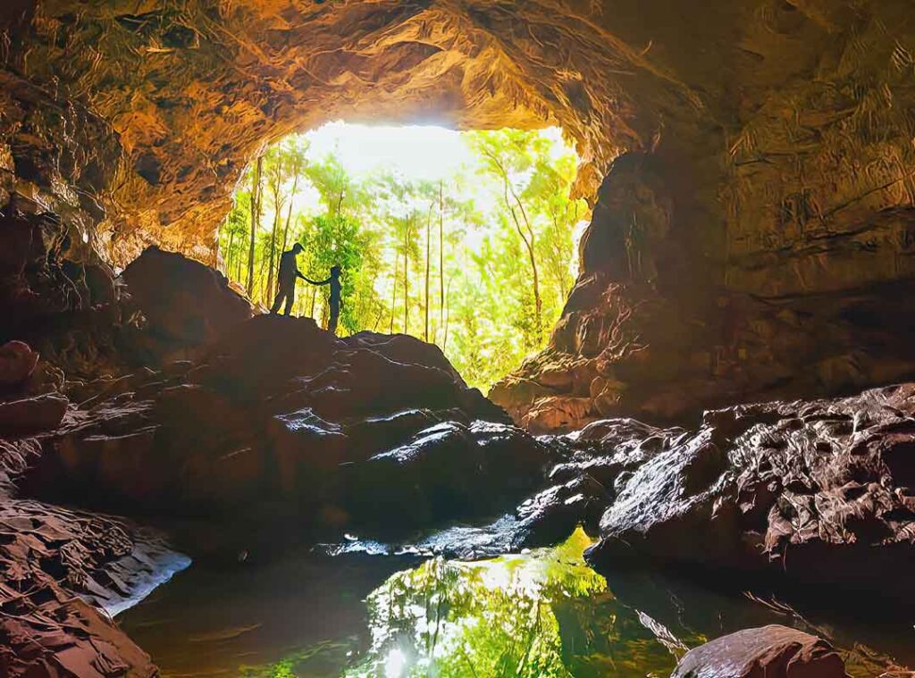 Visitors exploring Rio Frio Cave in Mountain Pine Ridge Belize surrounded by towering cave walls and natural river formations.