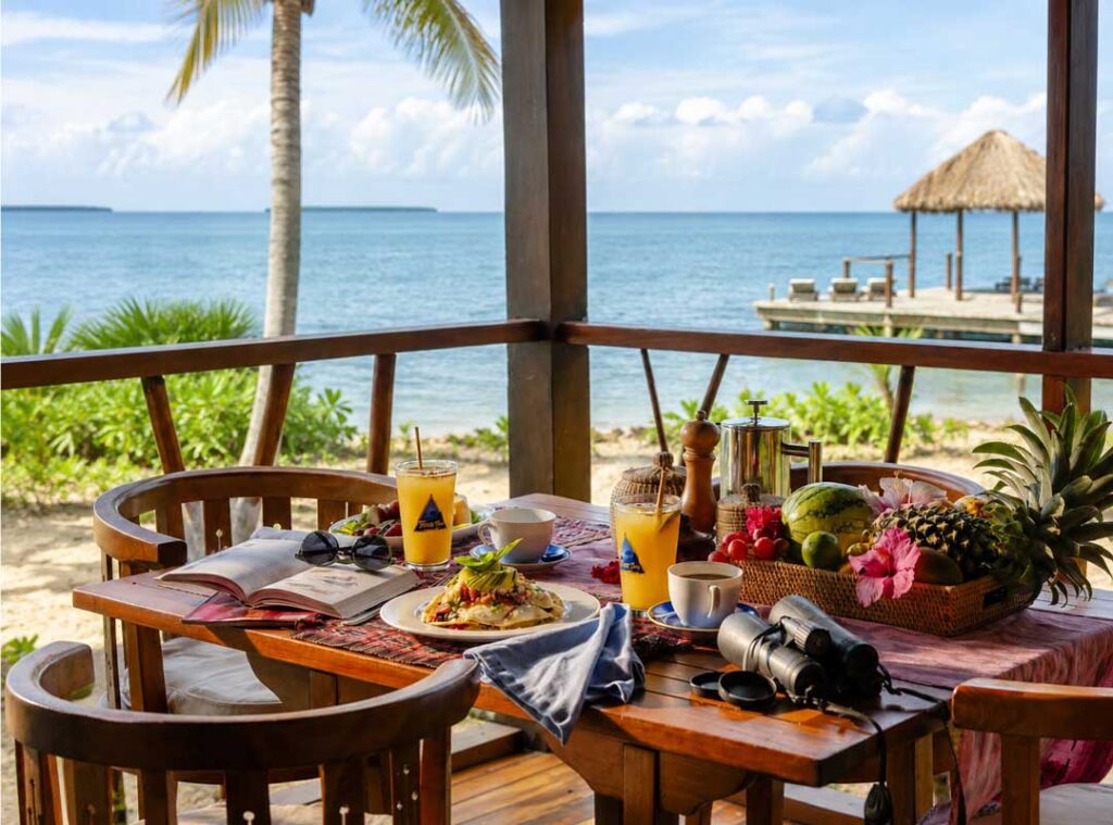 Tropical breakfast with fresh fruit and coffee served at a corner table overlooking the Caribbean Sea in Placencia, Belize.