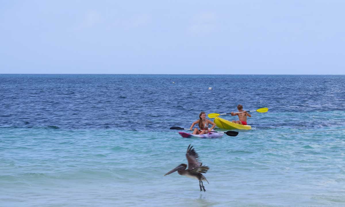 Reef-&-Rainforest-Family-Journey Belize Family Vacations with teenagers kayaking through clear turquoise water, enjoying a relaxed guided adventure along the Belize coast.