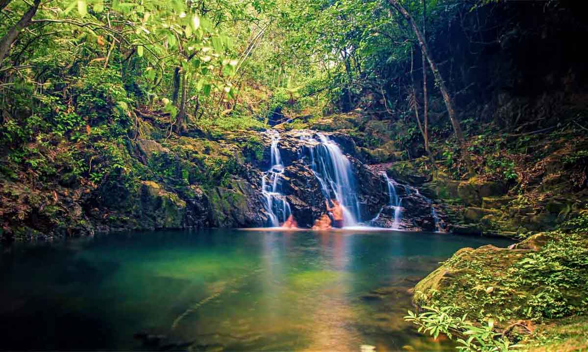 Soft-Adventure-Family-Journey Belize Family Vacations with parents and children enjoying a refreshing swim beneath a waterfall in the tropical forest of Belize.